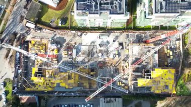 Gökyüzü görüntüsü modern bir evin dinamik yapısını şehir ortamında gösteriyor. Turnalar, canlı sarı malzemeler, kameralar tüm alanı görüntülemek için uzaklaşıyor.