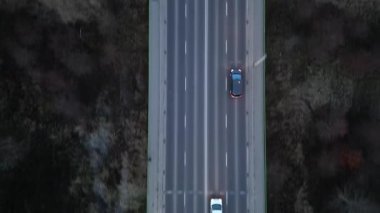 Akşamları otobanda seyahat eden arabaların hava görüntüsü dinamik hareketler sergiliyor. Otomobiller çevresindeki arazi ve kır yapısını çevreleyen yolda ilerliyor. Otomobiller yolculuk sırasında güzergahta sürüyorlar