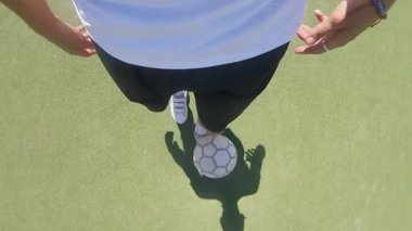 Futbolcu, sürekli hareket halinde atletizm ve hareketin özünü yakalayan canlı yeşil bir sahada futbol topuyla top sürme becerilerini gösteriyor.