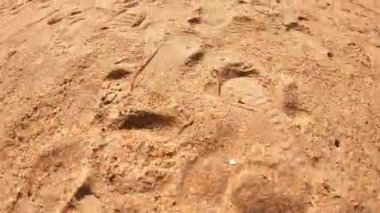 Kumlu arazinin yakın görüntüsü, kademeli doku değişikliklerini ve ayak izlerini gösteriyor, açık hava manzarasının doğal güzelliğini ve sükunetini vurguluyor.