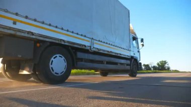 Kargo karavanıyla otoyolda giderken ve akşam vakti mal taşırken kamyoneti kapatın. Varış noktasına doğru hızla giden bir kamyon. Ulaşım ve lojistik konsept. Yavaş çekim Düşük görünüm.