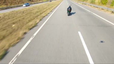 Yaz günü otoyolda hızlı giden bir adamın havadan çekilmiş fotoğrafı. Motosikletli, kır yolunda motosikletiyle yarışıyor. Yolculuk sırasında bisiklet süren bir adam. Özgürlük ve macera kavramı.