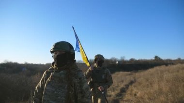 Askeri üniformalı genç kadın ve adam Meadow 'da ulusal pankarta gidiyor. Ukrayna bayrağıyla yürüyen Ukrayna ordusunun kadın ve erkek askeri. Rus saldırısına karşı zafer.