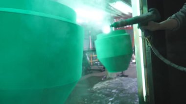 İşçi boya odasındaki detaylara yeşil boya püskürtüyor. Sanayi imalatında çalışan bir ressam. Uzman atölyede usta boya detayı. Üretimde parçaları boyayan adam. Yavaş çekim. Yakın çekim..