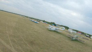 Hava perspektifi, çimenli arazide birden fazla park etmiş uçağın bulunduğu geniş bir havaalanı yakalar ve uçağın sakin ortamını ve düzenli bir şekilde yerleşimini vurgular.