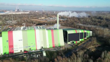Modern bir fabrikanın hava görüntüsü canlı renkli binaları üretim tesisleriyle sergiliyor, kamera endüstriyel alana yaklaştıkça dinamik sahneleri yakalıyor.