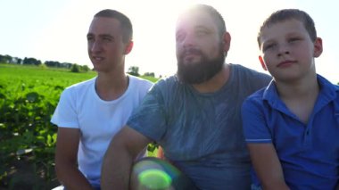Genç baba ve iki oğlu Yeşil Çayır 'da birlikte vakit geçiriyorlar. Baba, çocuklarına doğayı işaret ediyor. Mutlu aile güneşli bir günde kırsalda dinleniyor. Yavaşça kapat..