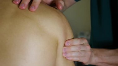 Yetenekli eller omuzlarında terapi masajı yapıyor, sakin bir ortamda kademeli baskı uygulamasını ve kasların gevşemesini gösteriyor..