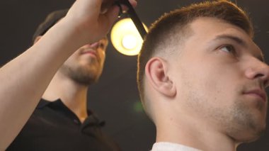 Profesyonel erkek kuaförü saç gencin salonda tarama profili. Yakışıklı adam saçı trendy berber dükkanında giyinmiş. Saç şekillendirme işlemi. Yan görünümü kapatmak yavaş hareket.