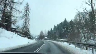 Karlı kış yolculuğunun zamanlaması pitoresk manzaralarda sergilenen şehir ve kırsal bölgelerde karla kaplı ağaçlarla kaplı yol ve dolambaçlı yolda giden araçlarla geçiş.