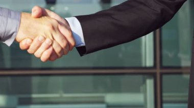 Genç meslektaşların şehir ortamında buluşup birbirlerini selamladıkları bir fotoğraf. İki başarılı iş adamı ofis binasının yakınında el sıkışıyor. Dışarıda iş tokalaşması. Yavaşça kapat..