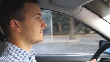 Şehir merkezinde ciddi yüz ifadeli otomobil kullanan genç bir iş adamı. Şehirde araba süren tişörtlü bir erkek sürücü. İşe gidip gelen yakışıklı bir adam. Kuaförden yan görüntü. Yavaşça kapat..