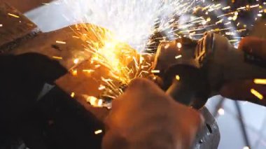 Profesyonel tamirci ya da tamirci kolları atölyede testere ile metal kesiyor. Erkek kaynakçının elleri garajda elektrikli çarkla çelik kesiyor. Üst Görünüm Kapat.