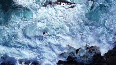 Çalkantılı okyanus dalgalarının dalgalı kıyı şeridine çarpması, kıyı ortamında su ve kayaların dinamik etkileşimini gösteriyor. Denizde fırtına. Güzel kıyı manzarası. Kapat.