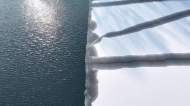 Koyu mavi suyla buluşan buz kenarının hava görüntüsü, kıyı şeridi boyunca görünen buz oluşumlarıyla donmuş yüzeyden açık suya kademeli geçişi gösteriyor. Güzel bir soğuk mevsimi. Üst görünüm