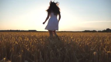 Güzel kız günbatımında buğday alanı çalışıyor. Genç kadın çayır ve enjoing özgürlük koşu. Yaz boş doğa kavramı olarak. Yavaş hareket kapatmak.