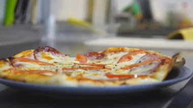 Erkek aşçı biberli ve tuzlu biberli lezzetli bir pizzayı bitiriyor. Şef kurutulmuş otları serpiyor. Mutfakta bir tabakta lezzetli bir fırın tabağı. Yemek hazırlama konsepti.