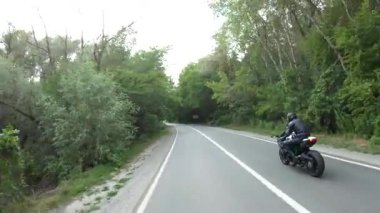 Orman yolunda motosiklet yarışı yapan bir motosikletli. Ormanın yakınındaki kırsal yolda kasklı bir adam spor motosikletine biniyor. Yolculuk sırasında bisiklet süren adam. Özgürlük ve macera kavramı. Hava görüntüsü.