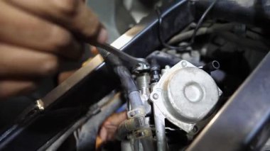 Tamircinin erkek elleri, işyerindeki aletleri kullanarak motorun motorunu tamir ediyor. Atölyede motor tamir eden profesyonel tamirci kolları. Garajda çalışan yetişkin bir tamirci. Yavaş çekim.