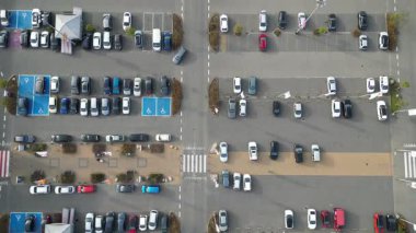 Alışveriş merkezinin yakınındaki işlek otoparkın hava görüntüsü, çeşitli araçların düzenli sırada sergilenmesi, kademeli kamera görüntüsü sahne dinamiklerini ve mekansal düzenlemeleri ortaya çıkarıyor