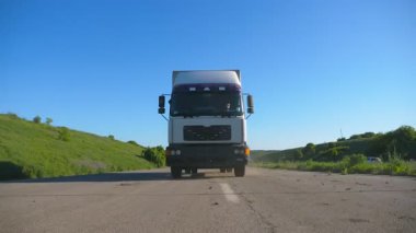Yaz günü mal taşıma karayolu üzerinde sürüş kargo römork ile kamyon ön görünümü. Beyaz kamyon arka planda güzel manzara ile kırsal üzerinden sürme. Yavaş mo Ön görünüm Kapat.