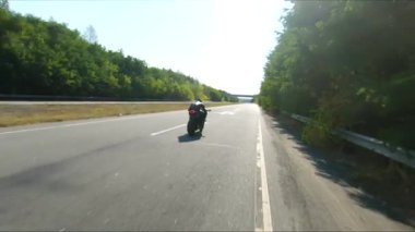 Bisikletçi yaz günü yol gezisi sırasında motosiklet sürüyor. Adam otoyolda modern spor motosikletle hızlı gidiyor. Motosikletli, kır yolunda motosikletiyle yarışıyor. Macera kavramı. Hava görüntüsü.