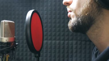 Erkek şarkıcı şarkı ses stüdyosunda mikrofona kulaklık. Duygusal olarak yeni şarkı kayıt genç adam. Yaratıcı müzisyen çalışma. Haritayı iş kavramı. Ağır çekim yan görünüm.