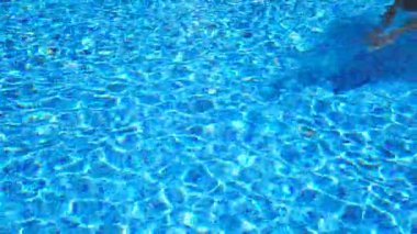 Otel havuzunda suyun altında yüzen şortlu tanınmaz bir adam. Yaz tatilinde otel havzasında yüzen adam. Güneşli bir günde yüzme havuzunda ferahlatıcı bir adam. Yavaş çekim. Yakın çekim..