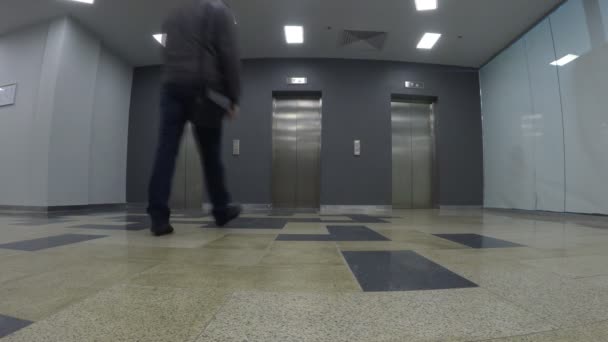 Jonge man wachten op een lift, wanneer ze aankomt. Weids uitzicht, van laag standpunt opgenomen — Stockvideo