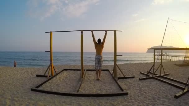 Hombre mostrando una fuerza impresionante, haciendo un músculo en la playa — Vídeos de Stock