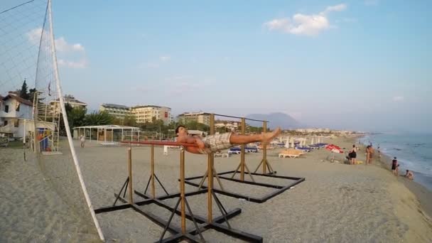 Hombre haciendo push up bares en la playa — Vídeo de stock