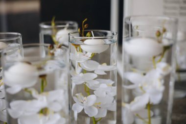 Beyaz güller, ranunculus, İran düğün çiçekleri, beyaz orkideler ve mumlar içeren geniş çiçek buketleri içeren romantik düğün masası süslemesi.