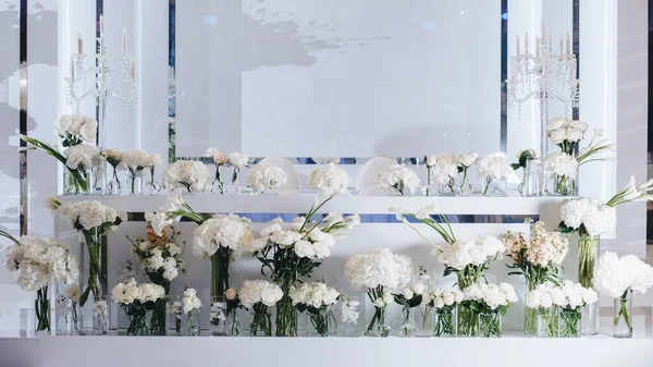 Decoração de layout de mesa de casamento romântico com grandes buquês florais exuberantes, incluindo rosas brancas, ranúnculo, buttercups persas, orquídeas brancas e velas — Fotografia de Stock