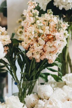 Beyaz güller, ranunculus, İran düğün çiçekleri, beyaz orkideler ve mumlar içeren geniş çiçek buketleri içeren romantik düğün masası süslemesi.