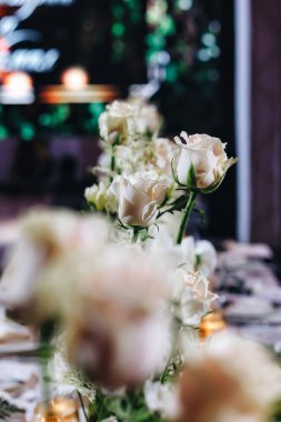 Beyaz güller, ranunculus, İran düğün çiçekleri, beyaz orkideler ve mumlar içeren geniş çiçek buketleri içeren romantik düğün masası süslemesi.