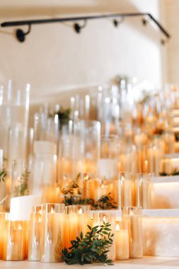 Beyaz güller, ranunculus, İran düğün çiçekleri, beyaz orkideler ve mumlar içeren geniş çiçek buketleri içeren romantik düğün masası süslemesi.