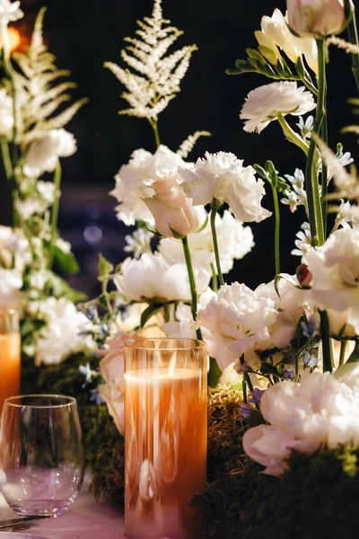 낭만적 인 웨딩 테이블 위의 라우트 디오르에는 흰색 장미, 라무 쿨 루스, 페르시안 버터 컵, 흰 난초 및 양초를 포함 한 크고 무성 한 꽃다발들이 있다 — 스톡 사진