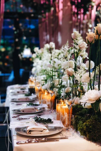 Decoração de layout de mesa de casamento romântico com grandes buquês florais exuberantes, incluindo rosas brancas, ranúnculo, buttercups persas, orquídeas brancas e velas — Fotografia de Stock