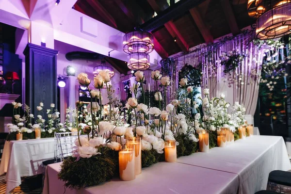 Decoração de layout de mesa de casamento romântico com grandes buquês florais exuberantes, incluindo rosas brancas, ranúnculo, buttercups persas, orquídeas brancas e velas — Fotografia de Stock