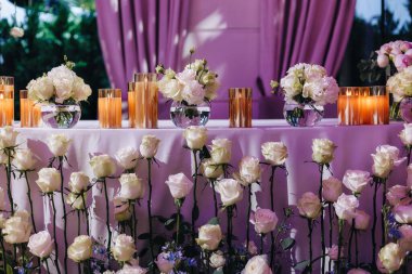 Beyaz güller, ranunculus, İran düğün çiçekleri, beyaz orkideler ve mumlar içeren geniş çiçek buketleri içeren romantik düğün masası süslemesi.