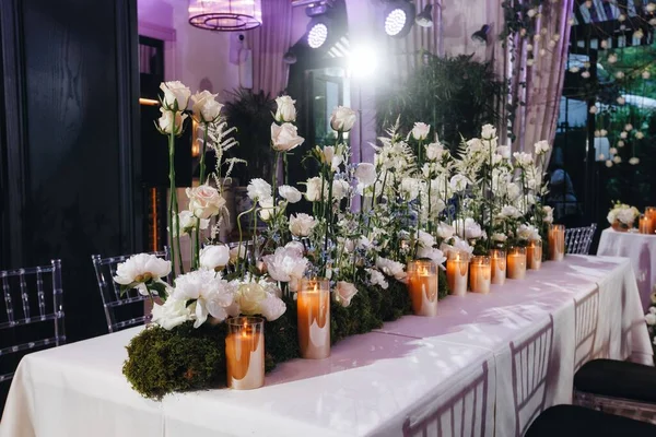 Decoração de layout de mesa de casamento romântico com grandes buquês florais exuberantes, incluindo rosas brancas, ranúnculo, buttercups persas, orquídeas brancas e velas — Fotografia de Stock