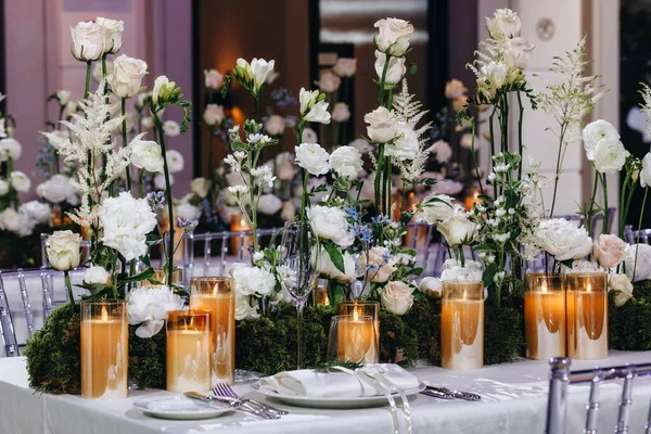 Decoração de layout de mesa de casamento romântico com grandes buquês florais exuberantes, incluindo rosas brancas, ranúnculo, buttercups persas, orquídeas brancas e velas — Fotografia de Stock