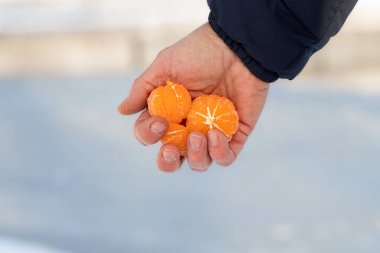 Elinde soyulmuş mandalina tutan adam.