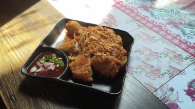 Yemek masasında siyah tabakta kızarmış tavuk, Tayland usulü kızarmış tavuk.