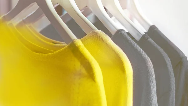 Bright illuminating yellow and gray colours clothes on hangers. Royalty Free Stock Images