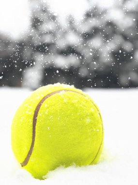 Noel arkaplanındaki karların üzerinde tenis topu ve düşen kar taneleri..