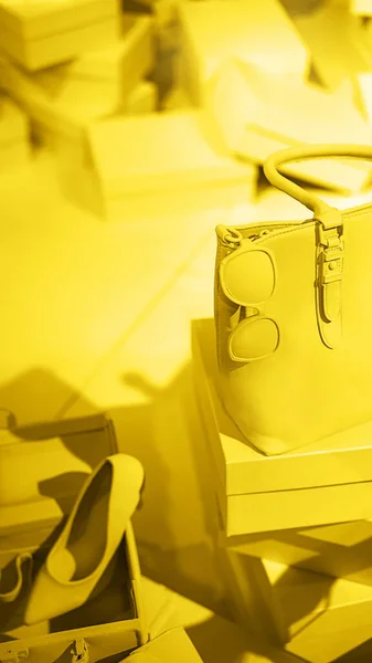 Brillante iluminando zapatos de tacón alto amarillo, bolsa y gafas en gris. — Foto de Stock