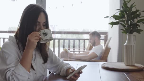 女の子は台所で朝コーヒーを飲み 電話でニュースを読む — ストック動画