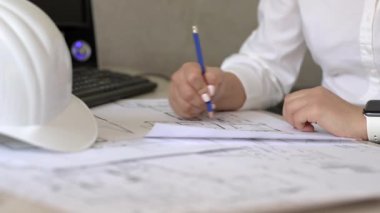 İnşaat mühendisi kağıt planları hakkında notlar alıyor