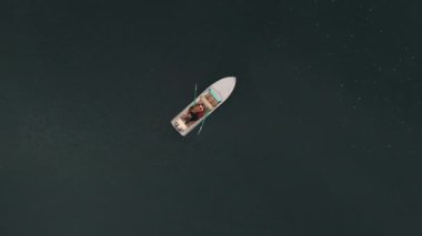 Yukarıdan bak. Adam gölün ortasındaki teknede yatıyor.